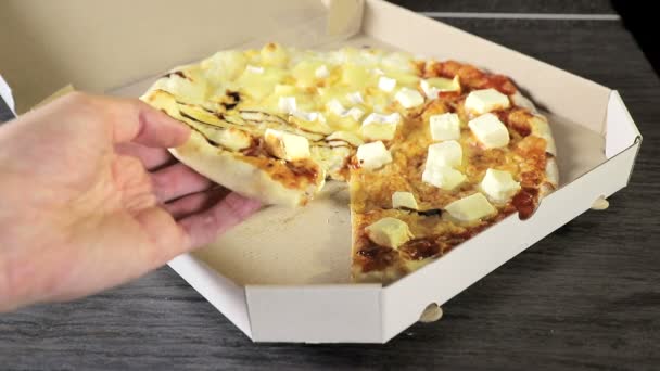 Mano de cerca que toma una rebanada de pizza de una caja de cartón blanco. Mano sosteniendo una rebanada de pizza cuatro quesos — Vídeos de Stock