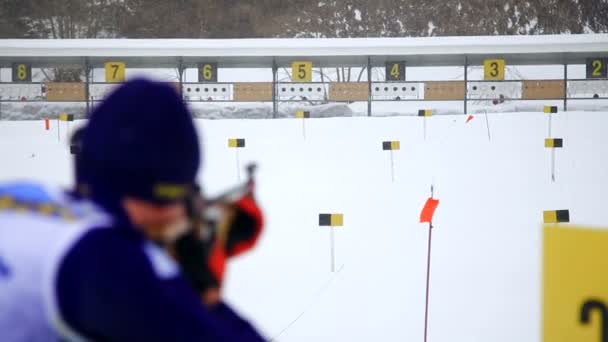 Un skieur tire un fusil sur une cible. Skieur prend part à la course de biathlon, debout vers la cible et a fait un tir . — Video