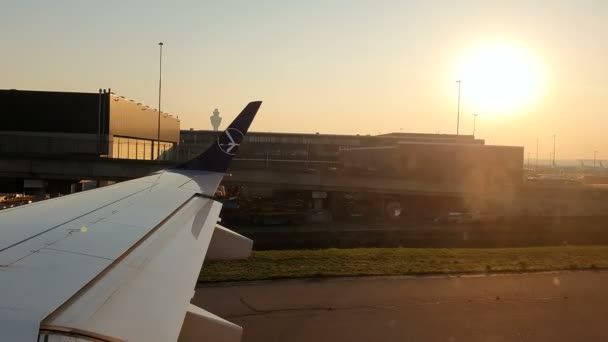 AMSTERDAM, PAYS-BAS 05 août 2019 : Soleil du matin à l'aéroport d'Amsterdam Schiphol. L'avion roule vers la piste. Vue par la fenêtre de l'avion du lever du soleil à l'aéroport — Video