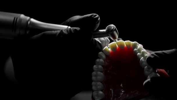 Close-up of a dentist practicing on a mock-up of a skeleton of teeth using a drill machine. the dentist deftly practices aligning the front teeth on the layout — Stock Video