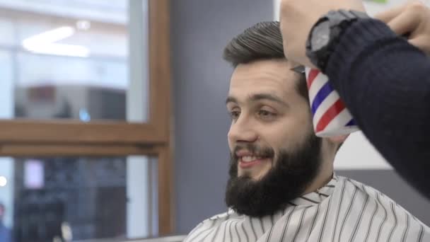 Haircut in a Barbershop. Barber combs the clients hair and sprinkles water on his hair. The smile of a man who gets a haircut — Stock Video