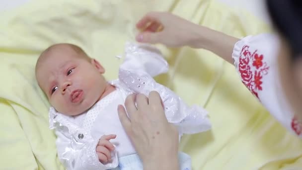 Mãe veste um bebê recém-nascido pequeno em um terno branco — Vídeo de Stock