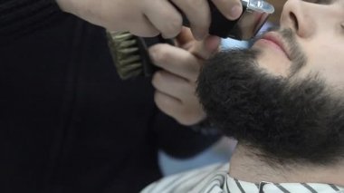 Berber, müşterilerin saçlarını sandalyede kesmek için makas kullanır. Yakın çekim makası saçlarını kesiyor.