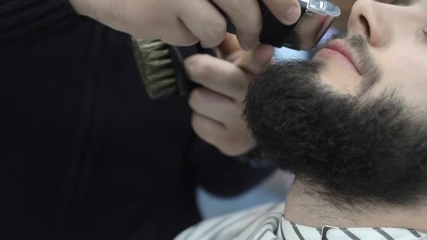 Barber uses a clipper to cut the clients hair in a chair. Close-up clipper shaves off hair — 비디오