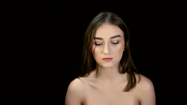 Fashion girl with black hair, brunette turns her head and swings her hair and effectively looks at the camera. Model posing on a black background — Stock Video