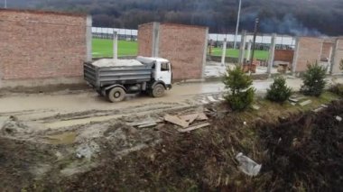 Kamyonetin arkasındaki hava manzaralı uçuş yağmurlu bir havada yol boyunca ilerliyor. İnşaat alanındaki bataklık.