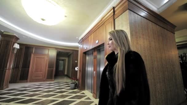 La donna d'affari lascia l'hotel. Una giovane ragazza carina sta camminando nell'atrio dell'hotel. Sparatoria da dietro — Video Stock