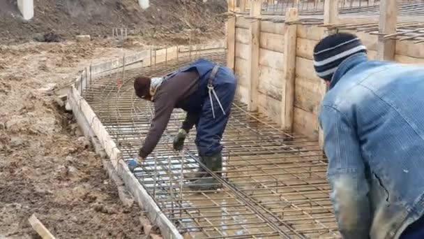 İki işçi beton dökmek için demirden bir çerçeve inşa ediyorlar. — Stok video