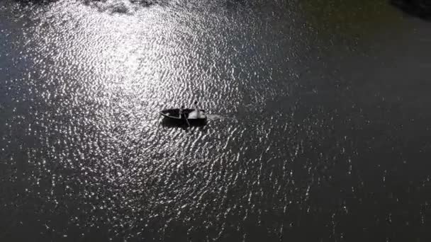 Foto aérea de novias nadando en un bote rojo. El sol brillante se refleja en el lago creando un reflejo y resplandor parpadeante . — Vídeos de Stock