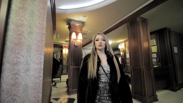 La donna d'affari lascia l'hotel. Una giovane ragazza carina sta camminando nell'atrio dell'hotel. Sparatoria da dietro — Video Stock