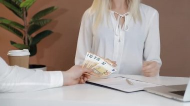 Ofisteki adam bir kadına Avrupa para birimi olarak banknotlar veriyor. Kadın Euro fonunu alır ve transfer eder..