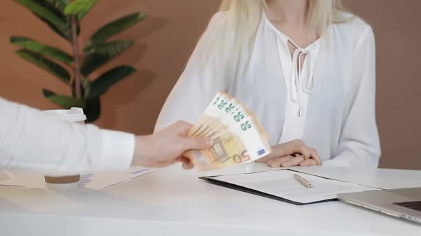 Mannen på kontoret ger sedlar i euro valuta till en kvinna som vägrar att ta emot pengar och visar vägran med händerna. — Stockvideo