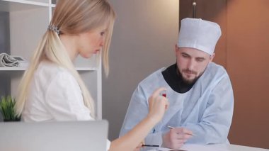 Hemşire, doktor test tüplerine laboratuarda testler gösteriyor. Kırmızı bir sıvıyla test tüpünü inceleyen bir doktor.