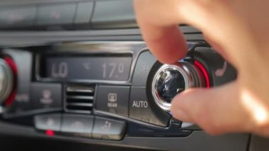 Erkek parmaklarının yakın plan çekimi arabanın iç sıcaklığını ayarlar. Kocanın eli düğmeyi çevirir ve arabanın rahatlığını ayarlar.