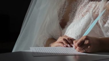 Kız elinde mavi bir kalem tutuyor ve bir deftere yazıyor. Kız beyaz iç çamaşırı giyiyor. Defterde bir güneş ışığı parlıyor..