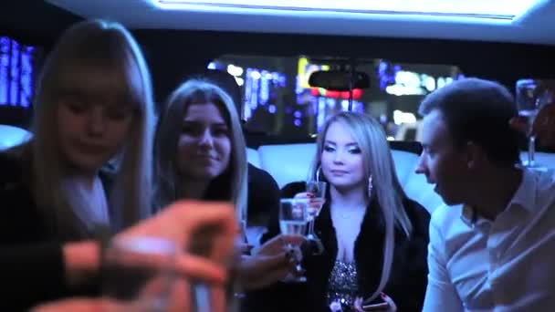 Jong meisje met vrienden viert haar verjaardag in een limousine. Mensen heffen glazen champagne. Nachtlicht van verschillende kleuren valt op hun gezichten. — Stockvideo