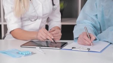 Ofisteki tablette çalışan doktorların yakın çekimleri.