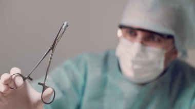 Doktor elinde tıbbi bir aletle mavi bir tablet tutuyor ve tableti inceliyor..