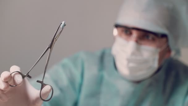 De arts houdt een blauwe tablet vast met een medisch instrument en onderzoekt de tablet. — Stockvideo