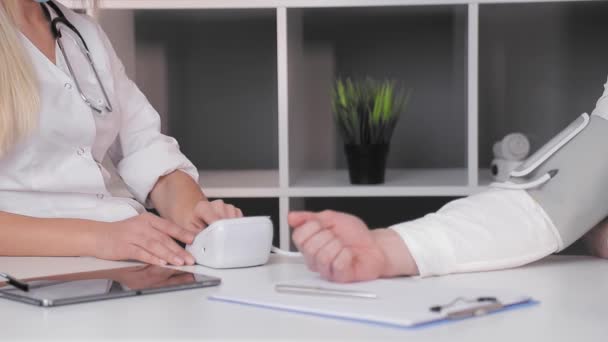 Врач мужского пола в офисе измеряет давление пациента-мужчины крупным планом — стоковое видео