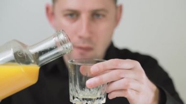 Adam bardağa portakal suyu dolduruyor. Bir adam mutluluk dolu bir yudum portakal suyu alır.