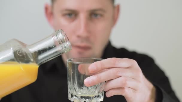 Mann gießt Orangensaft in ein Glas. Ein Mann nimmt einen Schluck Orangensaft mit glücklichen Gefühlen — Stockvideo