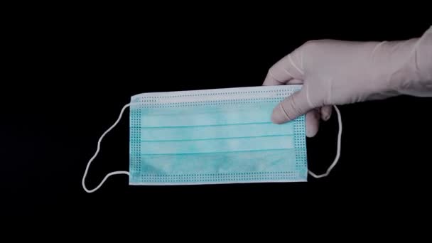 Рука медсестер ставить захисні медичні рукавички на чорну поверхню, одна медична маска — стокове відео