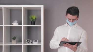 Koruyucu tıbbi maskeli doktor ofisindeki tablette çalışıyor..