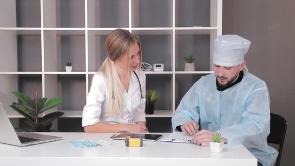 Läkare en man och en kvinna som arbetar på kontoret med en tablett vid bordet. — Stockvideo