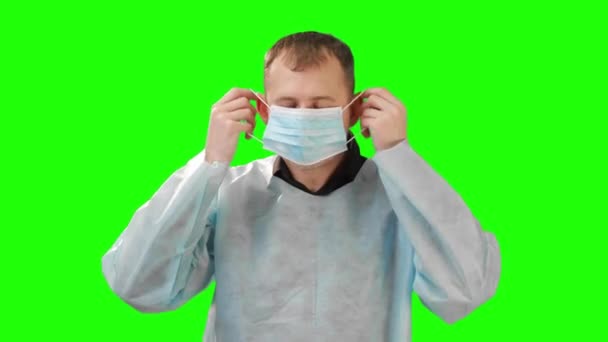 Tıp bilimcisi ameliyat önlüğü giymiş ve koruyucu bir maske takıyor. Chromakey 'deki video. — Stok video