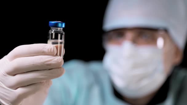 실험실 보조원은 COVID-19 코로나 바이러스 백신 병을 손에 들고 있다. 바이러스에 대항하는 백신. — 비디오