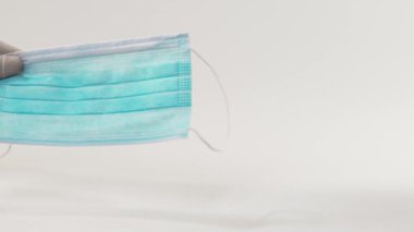 Tıbbi eldiven giyen hemşire hastalıklı bir tıbbi maske takıyor. Doktor, tıbbi maskeyi hastaya iletir..