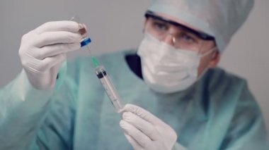 Bulaşıcı doktor elinde bir şırınga ve Covid-19 Coronavirus aşısı tutuyor. Doktor şırıngaya aşı enjekte ediyor..