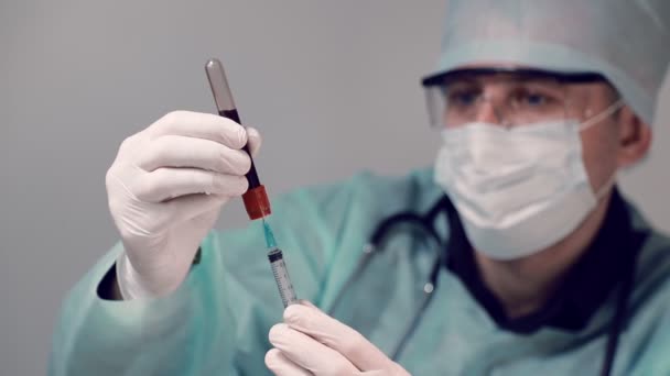 Dokter in het laboratorium, zuigt bloed uit een reageerbuis in een injectiespuit voor bloedanalyse. Bloedonderzoek op Covid19 coronavirus — Stockvideo