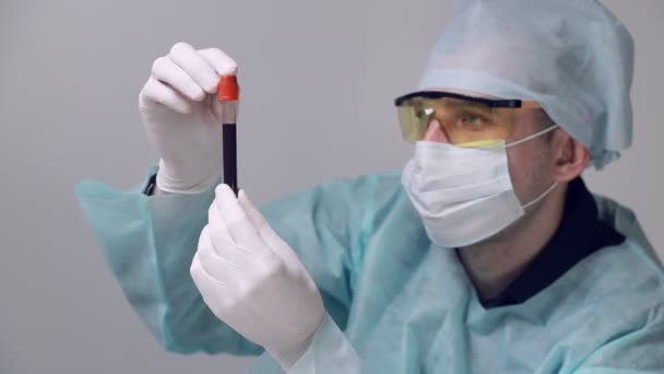 Der Arzt führt eine Blutprobe durch. Der Techniker hält ein Röhrchen mit einem Bluttest in der Hand und untersucht das Blut. Bluttest auf das Virus. — Stockvideo