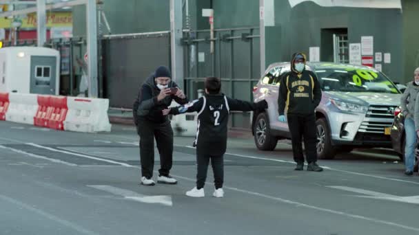 New York City, VS - 14 april 2020 Mensen en kinderen worden gefotografeerd tegen de achtergrond van een lege Times Square in Manhattan in de nacht tijdens de codvid-19 coronavirus pandemie. — Stockvideo