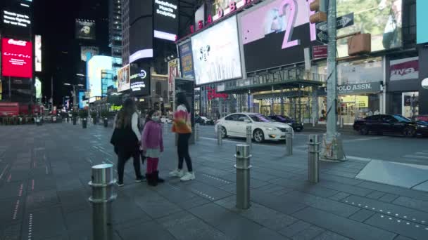 New York City, USA - 14 april 2020 Människor och barn fotograferas mot bakgrund av ett tomt Times Square på Manhattan under natten under coronaviruspandemin codvid-19. — Stockvideo