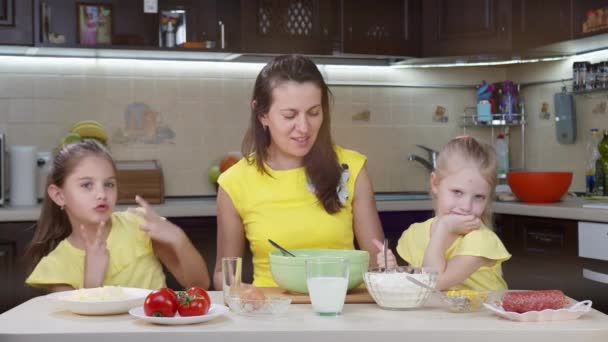 Mam en haar twee dochters hebben plezier in de keuken. Mam leert kinderen pizza maken. Gelukkige moeder en gelukkige kinderen koken samen in de keuken. — Stockvideo