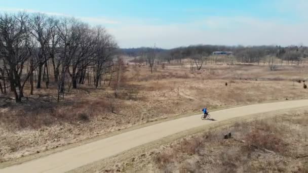 Hombre de vista aérea que monta una bicicleta en un parque estatal de Illinois. Paseo en bicicleta por el parque. El dron sigue a un ciclista que monta en un carril bici . — Vídeos de Stock