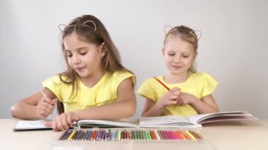 Komik ve komik çocuklar. Masadaki çocuklar dans edip yaratıyorlar. İki çocuk bir masada oturuyor ve boyama kitabı boyuyorlar..