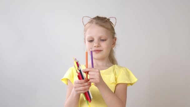 Маленька дівчинка тримає кольорові олівці в руках. Дівчина готується малювати . — стокове відео
