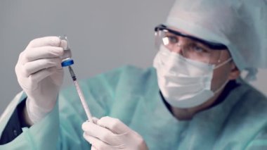 Bulaşıcı doktor elinde bir insülin şırıngası ve bir şişe Covid-19 Coronavirus aşısı tutuyor. Doktor şırıngaya aşı enjekte ediyor..