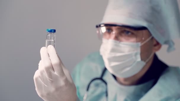 Der Laborant hält ein Fläschchen mit COVID-19 Coronavirus-Impfstoff in der Hand. Impfstoff gegen das Virus. — Stockvideo