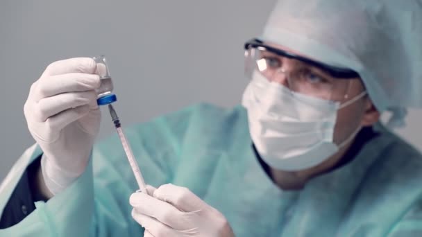 전염병 의사는 인슐린 주사기와 코비 디온 -19 코로나 바이러스 백신 병을 손에 들고 있다. 의사가 주사기에 백신을 주사하다. — 비디오