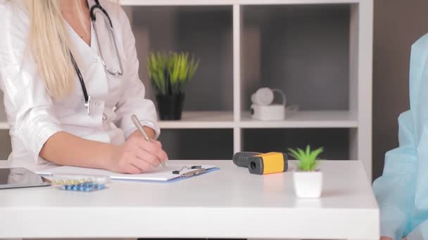 Primer plano de la mano de una doctora, anotando información sobre el paciente con una pluma . — Vídeos de Stock