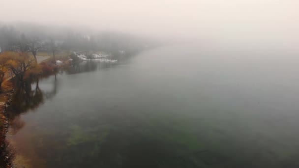 Vliegtuig Vliegen over het meer bij zware mist en bewolkt weer. De dijk van het meer op een mistige dag. — Stockvideo