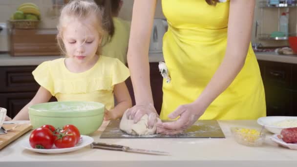 A gyerekek nézik, ahogy anya pizzatésztát főz közelről. A nők kezei dagasztják a tésztát.. — Stock videók