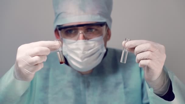 Zaměstnanec Timsovy laboratoře si vzal dvě zkumavky s různými studiemi. Laboratorní asistent vyšetřuje krev ve zkumavkách. — Stock video