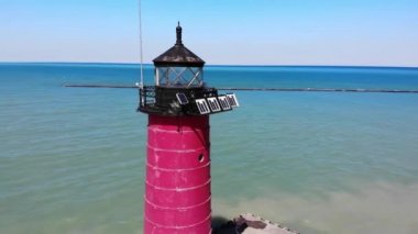 Güneşli bir günde deniz kenarında kırmızı deniz feneri. Kırmızı bir deniz fenerinde bir kuadkopterden görünüm.