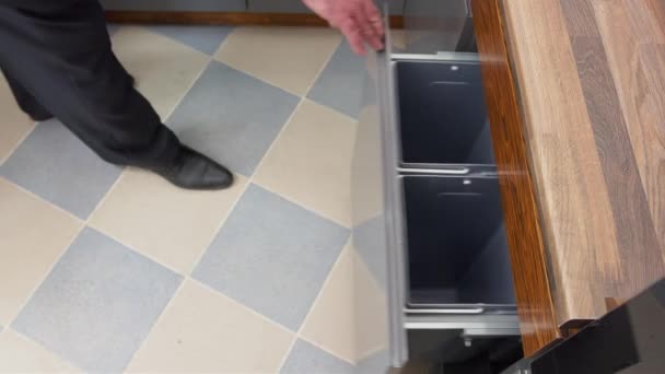 Sorting garbage at home. A man in the kitchen opens a trash can. Empty buckets with four sections for sorting garbage at home. — Stock Video